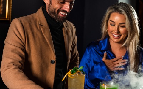 women and man looking at drink with smoke