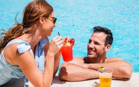 a couple sipping drinks together by the pool