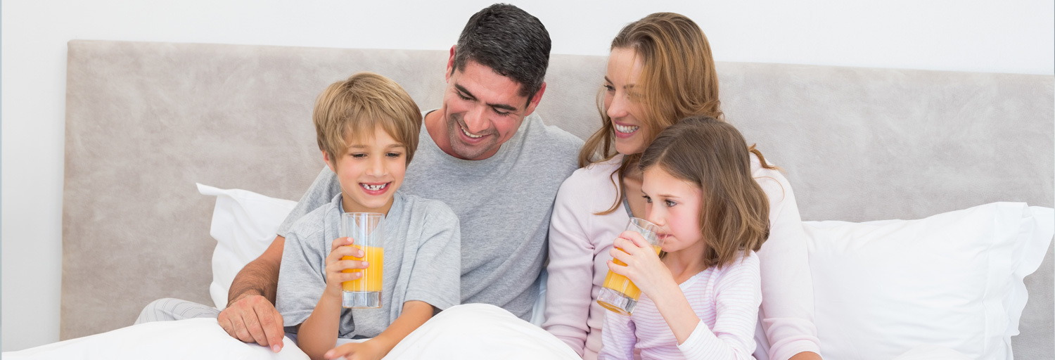 family sitting in bed drinking juice