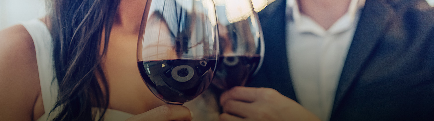 two people holding glasses of red wine