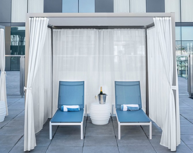 pool cabana with two blue chairs and a white curtain around it