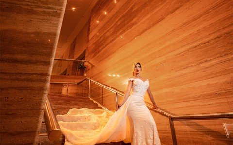 A bride walking down a low lit wooden staircase.