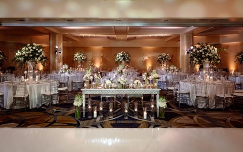 Dimly lit room with linen tables and huge floral centerpieces.