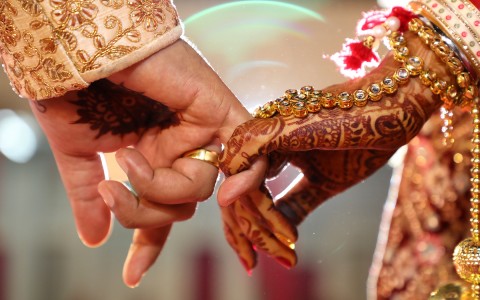 Two people holding hands and wearing gold jewelry.