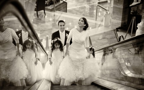 A black and white image of a bride, groom, and two little girls going up an escalator.