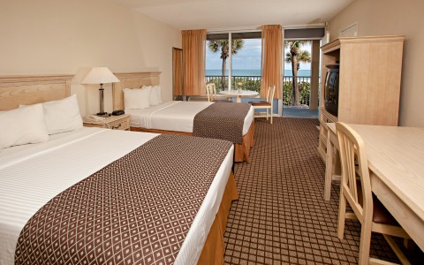 Room with two double beds, desk, Tv & balcony with ocean view 