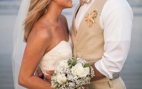Groom kissing bride on forehead on the beach