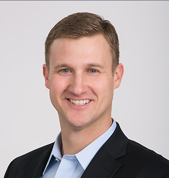 headshot of team member in suit jacket and blue button down