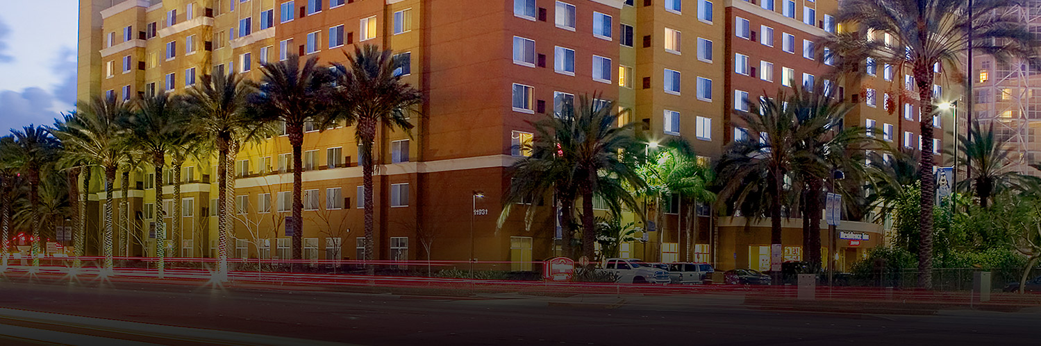 exterior of hotel building with palm trees and dark overlay