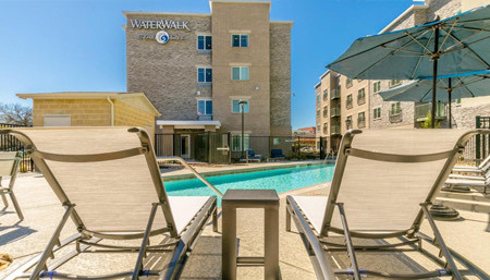 pool with two sun chairs around and one building behind