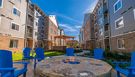 Exterior of hotel on a sunny day with firepit and blue lawn chairs