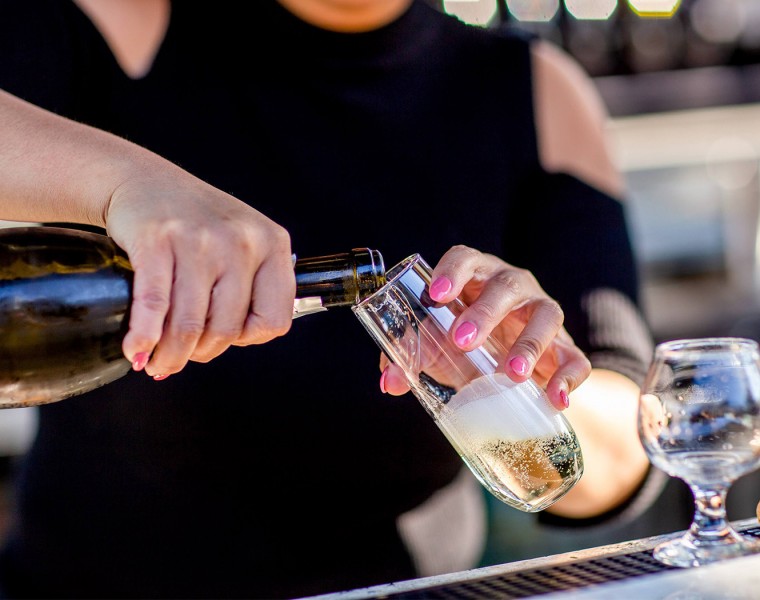 A bartender pouring champagne in a stemless flute.