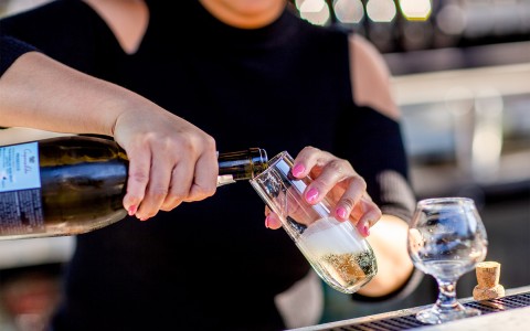 A bartender pouring champagne into a flute.