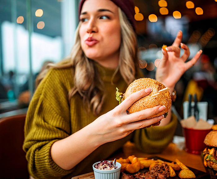 A woman holding a burger in her hands and looking to her right.