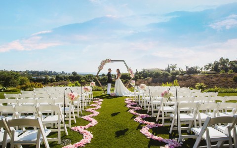 pink flower petals on the aisle of an outdoor wedding