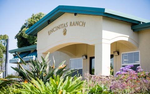 the encinitas ranch entrance with colorful plants and flowers in front