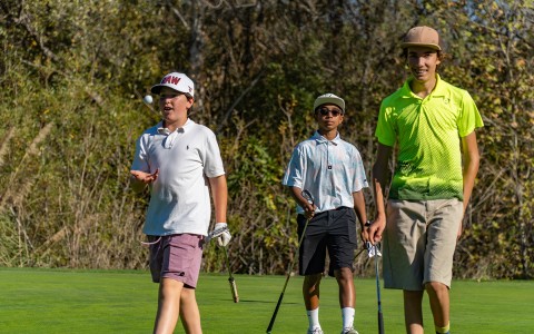 three young kids playing golf during the day