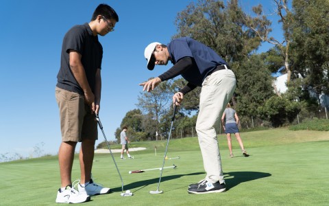 novice golfers taking instruction from a golf coach on the golf course
