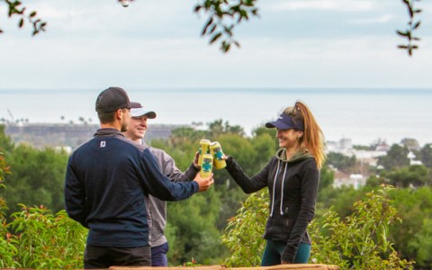three people clinking their beers in a lounge area on the course