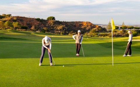 three women playing golf near the yellow flagstick