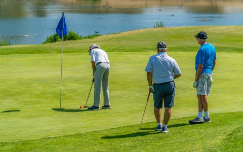 a small group of men playing golf on the course 