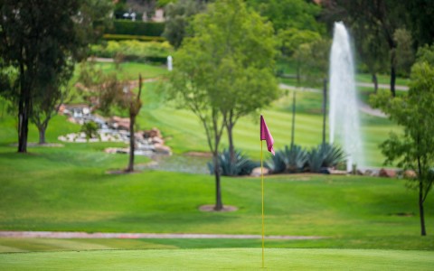 a red flagstick with a fountain in the background