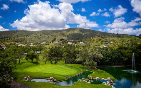 a drone shot of the large property and golf course with tall hills and mountains in the distance