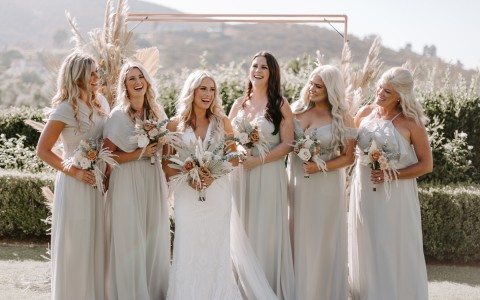 bridesmaids wearing light gray dresses and standing with the bride