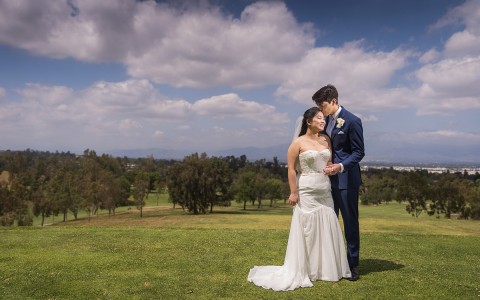a bride and groom standing close together on the golf course and posing for a photo