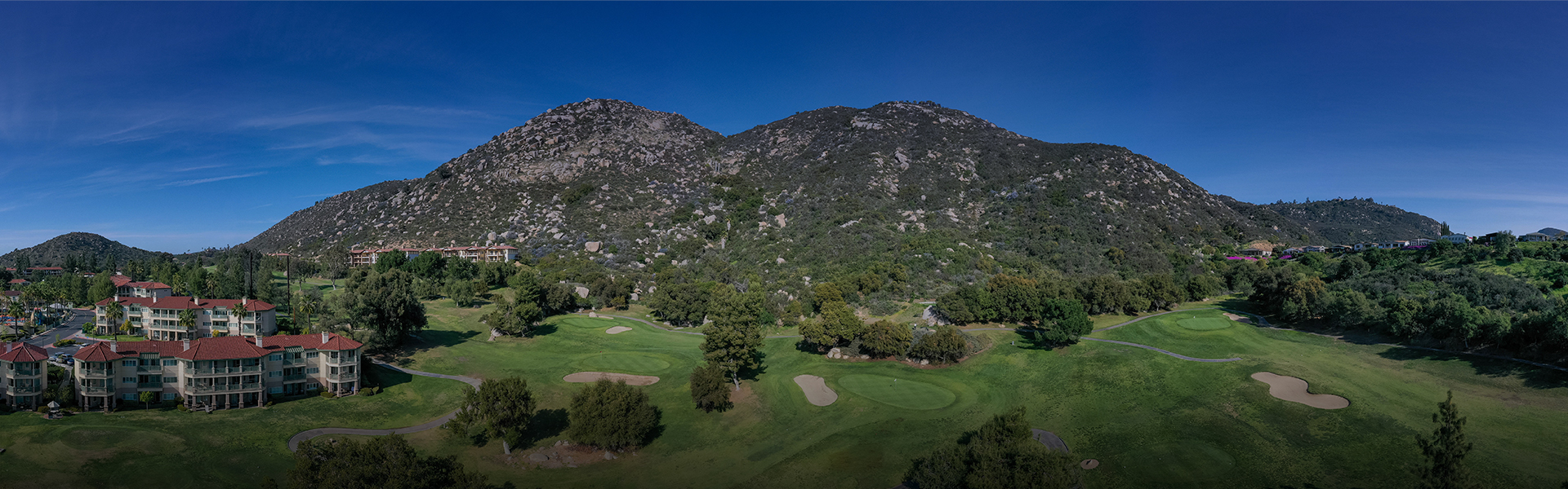 panoramic view of the course with a large mountain in the distance and clear blue skies