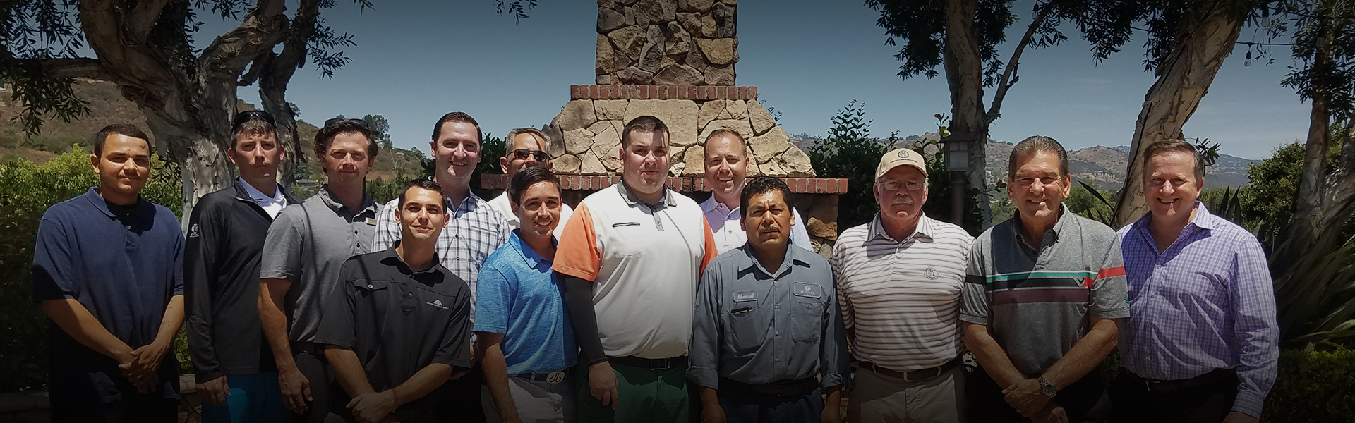 a large group of males standing outside in front of a stone fireplace