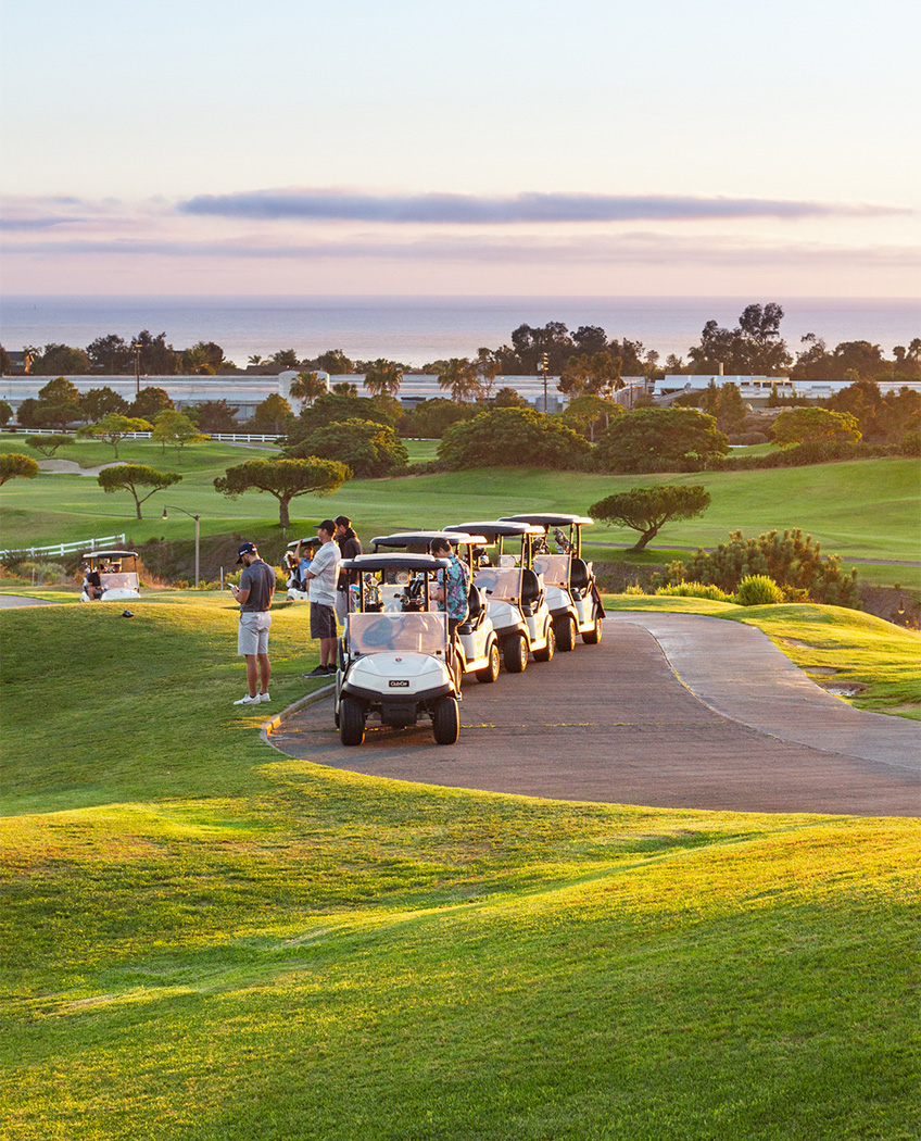four parked golf carts with golfers standing next to them