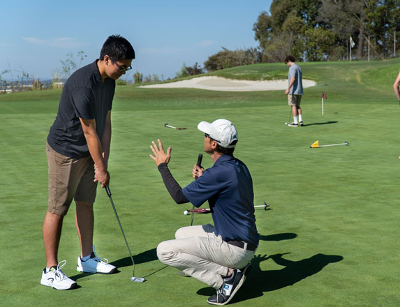an instructor giving tips to a young golfer 