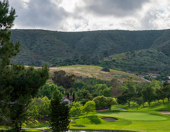 a large mountain with lush landscape located just beyond the golf course