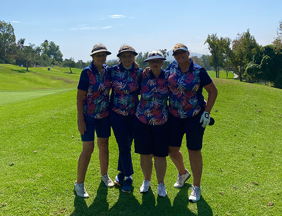 four women wearing tropical shirts on the golf course