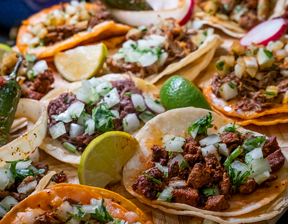 a wide variety of soft tacos served with chopped onion and limes