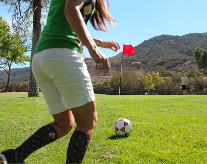 a girl running towards a ball while playing foot golf