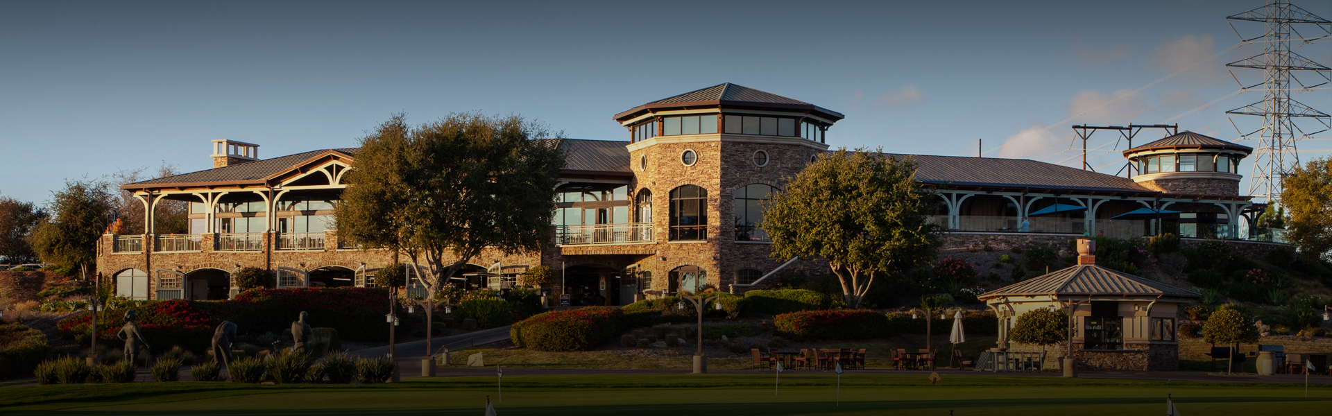 a large stone building overlooking the golf course and the sun setting to the left