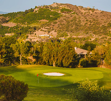 a large mountain behind the golf course and buildings