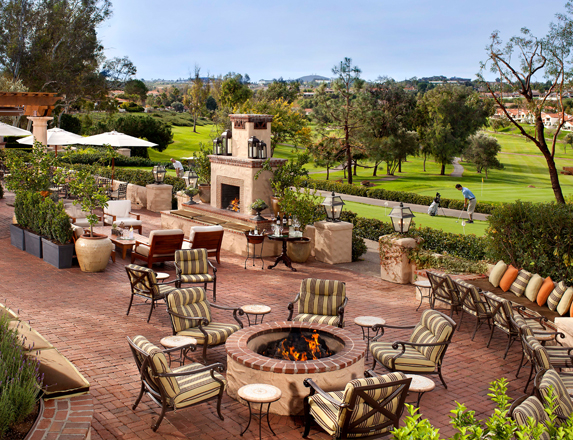 a patio with an outdoor fireplace and fire pit with lots of places to sit in cushioned chairs