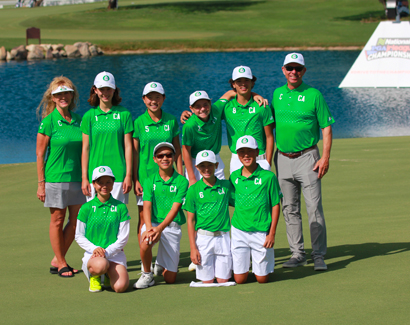 a small group of golfers wearing green shirts and posing on the golf course