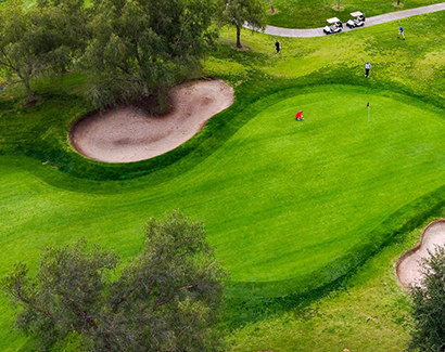 a drone shot of a large sand pit on each side of a red flagstick 