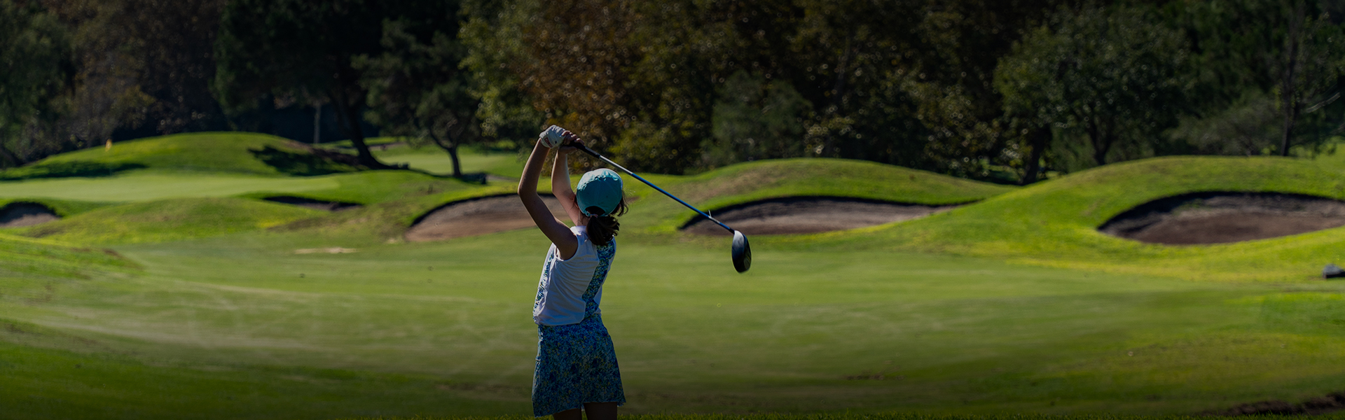 a young girl wearing a blue and white outfit while playing golf on the course