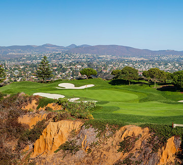 a clay ledge located to the left of the golf course and a large mountain range in the distance