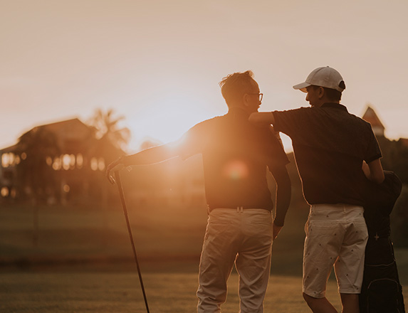 two men standing next to each other as the sun is setting in front of them