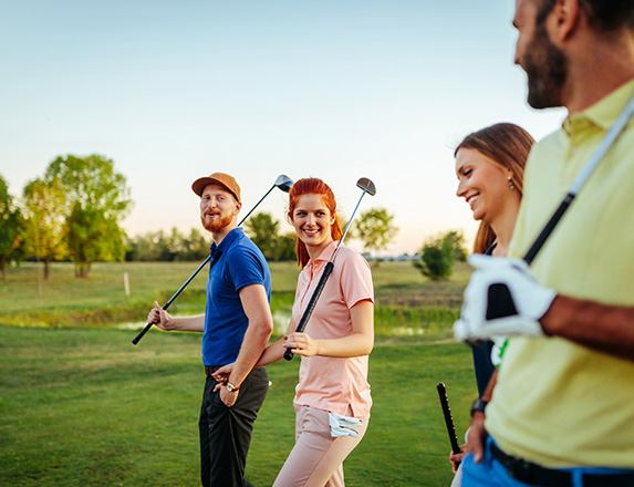 two couples walking on the golf course and smiling at each other