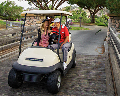 a couple on a white golf cart driving over a wooden bridge