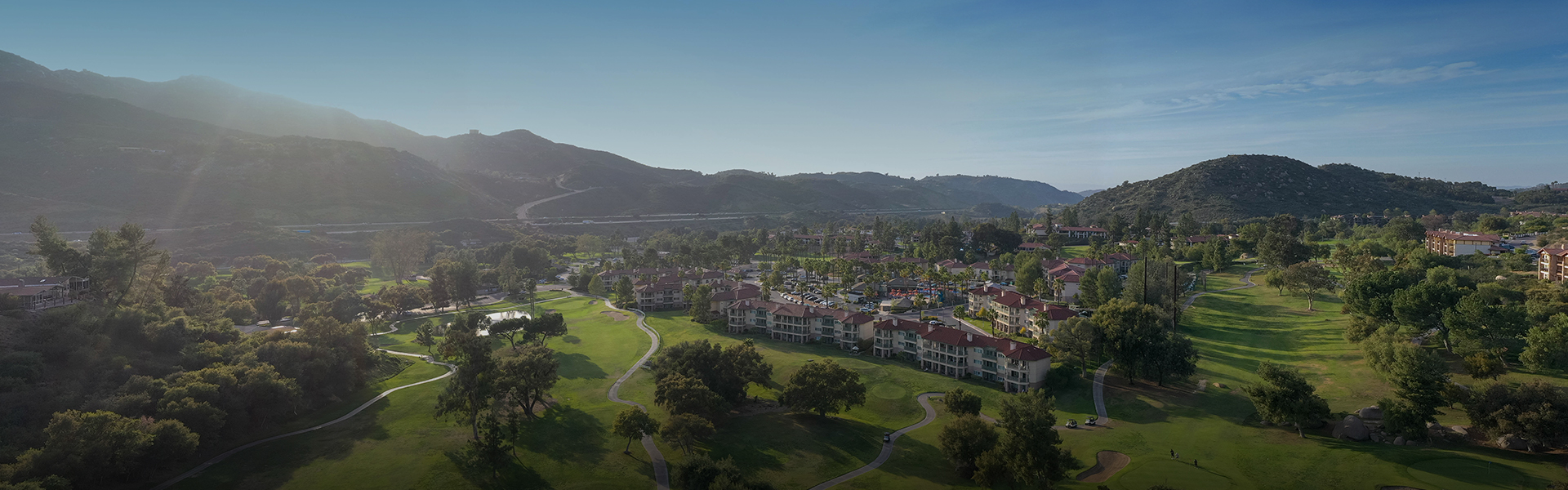 a panoramic shot of the large property with many buildings, trees, and mountains 