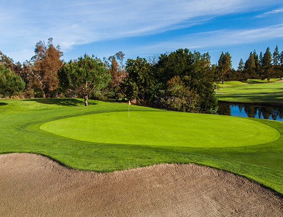 a large sand dune and a putting green with a small pond located to the right