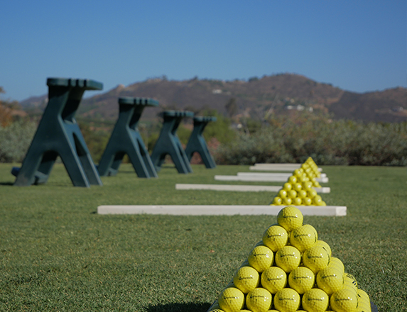 a close up of neatly stacked yellow golf balls on the driving range